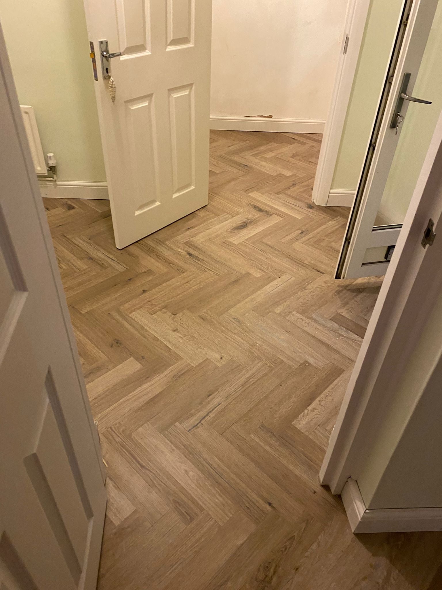 Seamless Karndean Herringbone LVT flooring installed throughout the hallway, kitchen and dining area without thresholds.